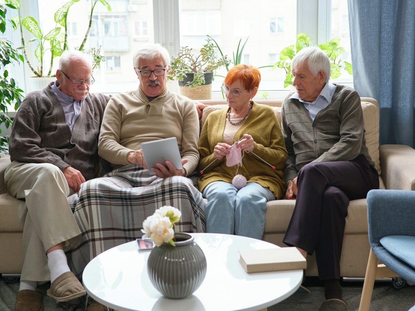 Pflege - Heinrich-Gerold-Haus Vier ältere Menschen sitzen auf einer Couch, schauen gemeinsam auf ein Tablet.