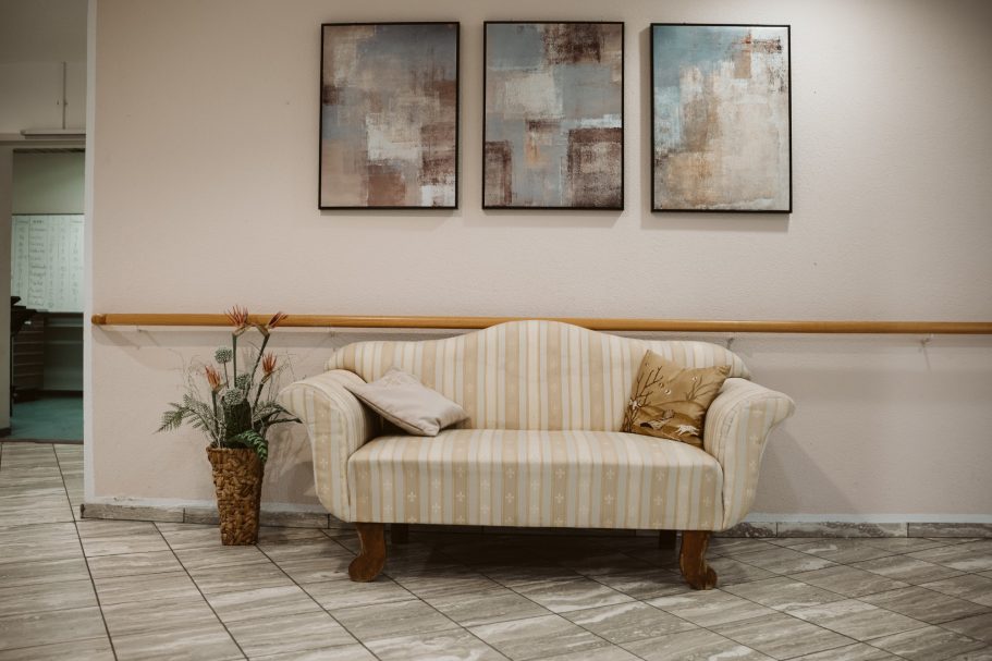Heinrich-Gerold-Haus DRK - Pflegeheim in Ober-Ramstadt Gemütliche Couch mit Kissen vor einer Wand mit abstrakten Bildern und einer Pflanze.