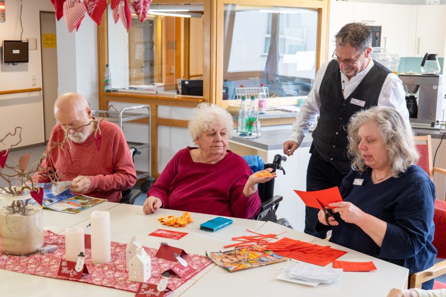 Heinrich-Gerold-Haus DRK - Pflegeheim in Ober-Ramstadt Vier Personen sitzen an einem Tisch, basteln mit buntem Papier und haben Freude am kreativen Arbeiten.